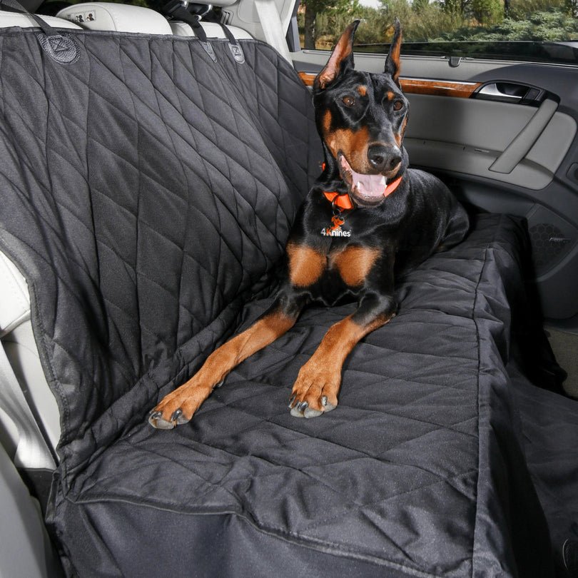 4Knines quilted black dog hammock seat cover installed in a car's back seat with a dog lying on it